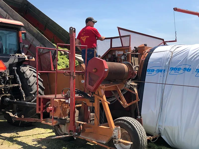 Farmer bagging chopped silage farmer using a blower to file silage bag
